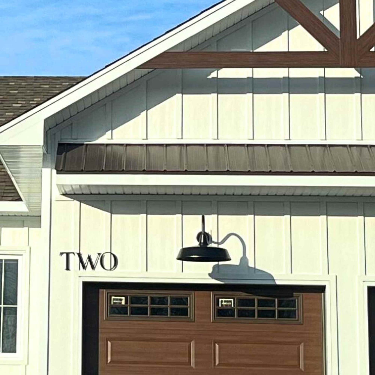 Garage door with 'TWO' sign and light fixture on a house exterior.