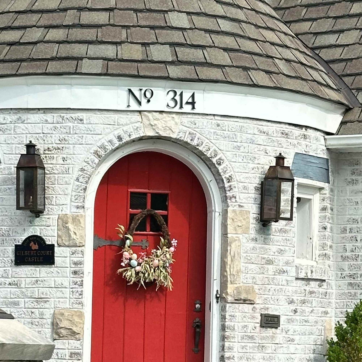 Red door with decorative wreath on a stone building with address 'No 314'.