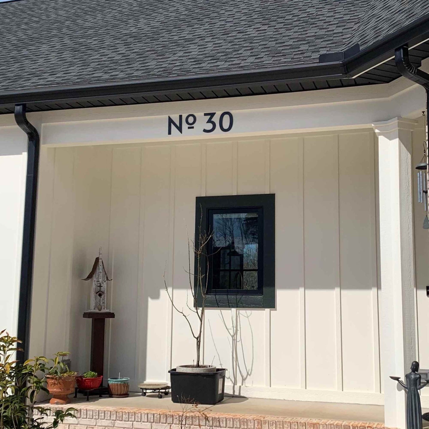 House exterior with number 'No 30' on a white wall, potted plants, and a small window.