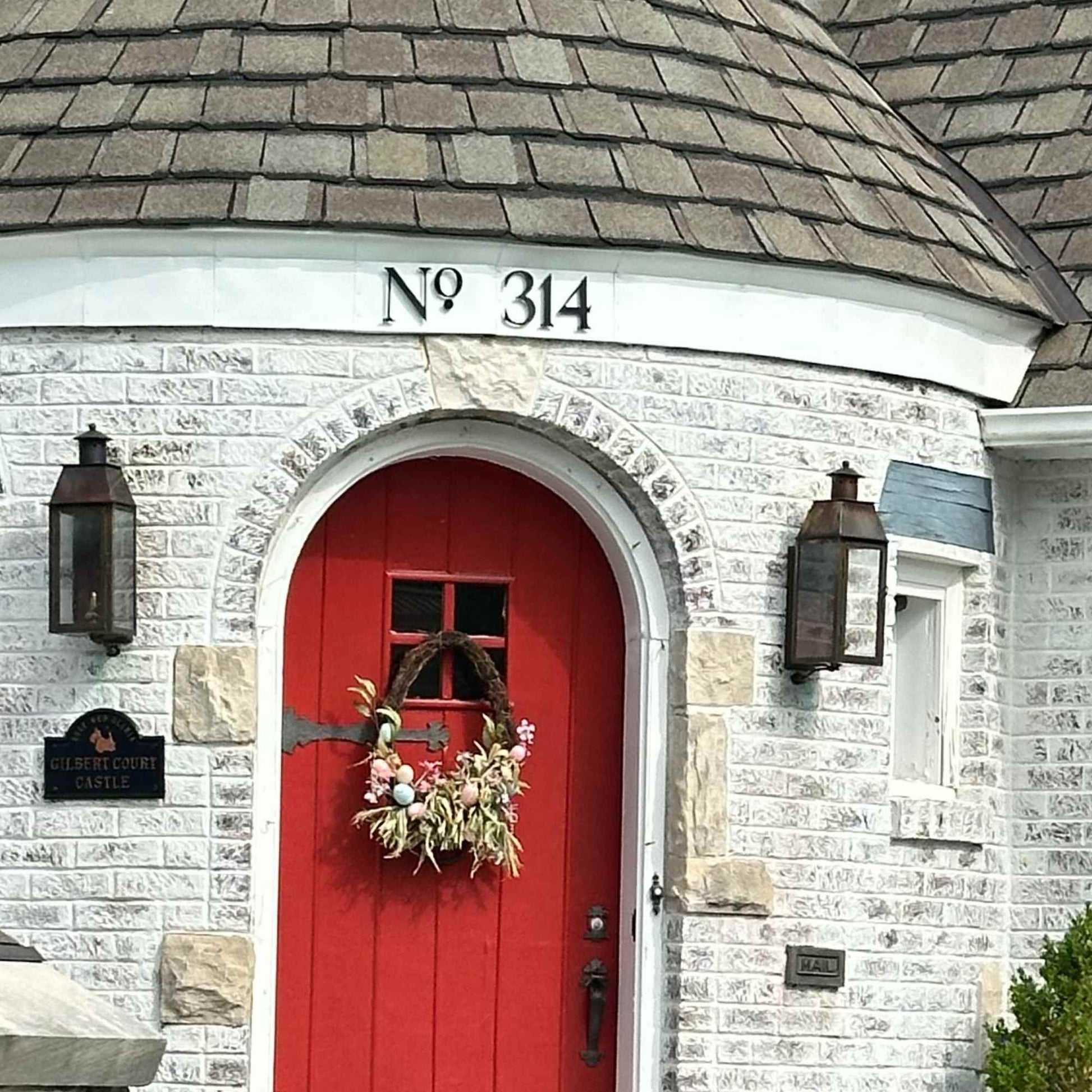 Red door with decorative wreath on a stone building with address 'No 314'.