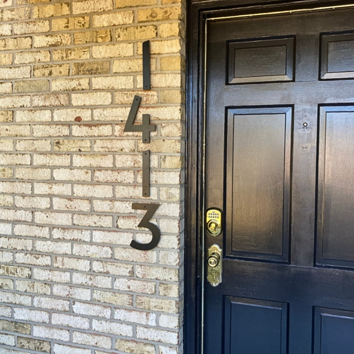 Black door with house numbers '1413' on a brick wall