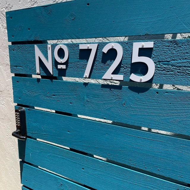 5 inch white house numbers from the Classic modern collection on a blue fence 