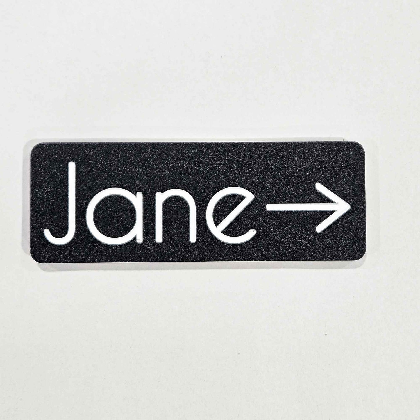 Black sign with 'Jane' and an arrow for an office door sign
