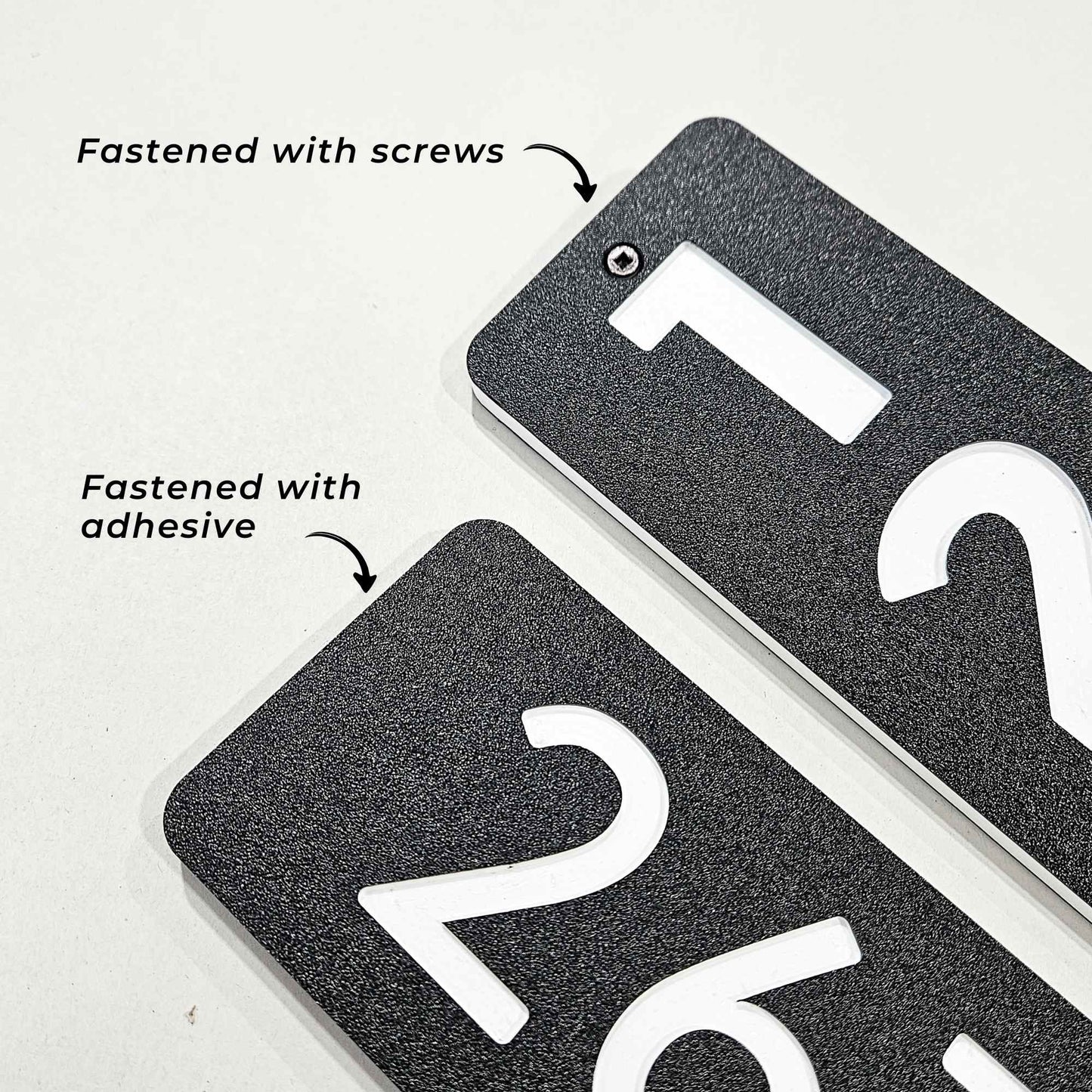 Close up detail of rectangle plaques showing the difference between adhesive fastening and screws