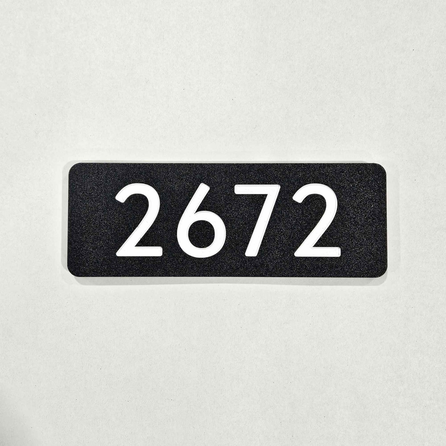 Black rectangular plate with white numbers '2672' 