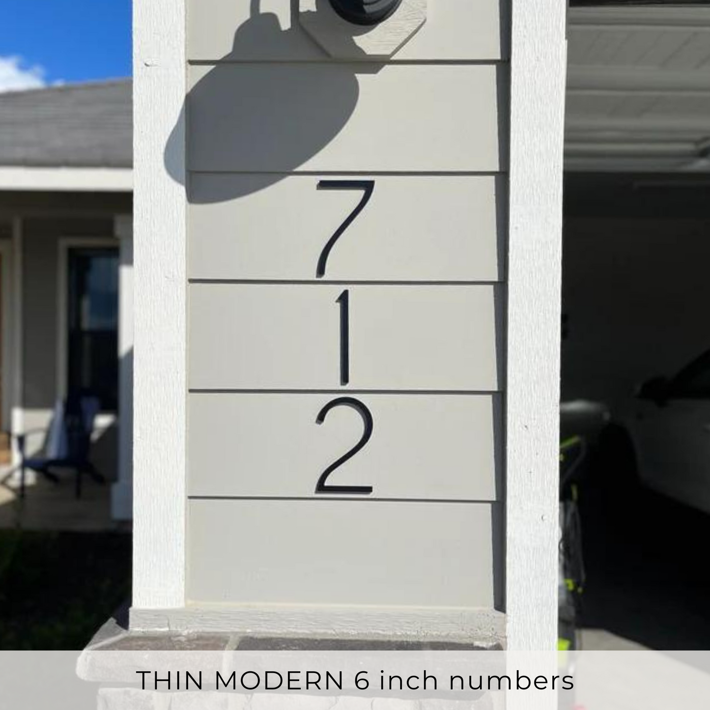 A white column with 'THIN MODERN 6 inch numbers' written on it, featuring black numerical digits representing a house address.