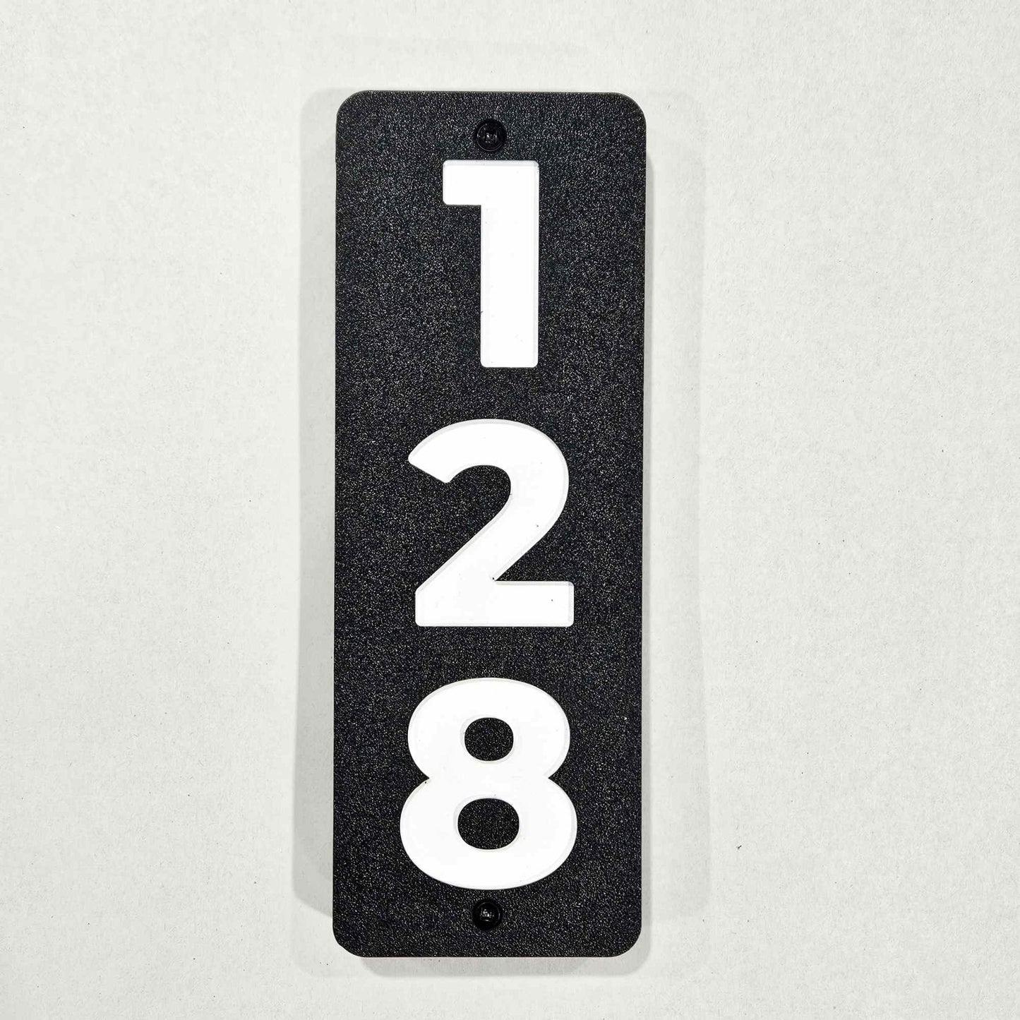 Vertical Black rectangular plate with white numbers '128' with screws for fastening